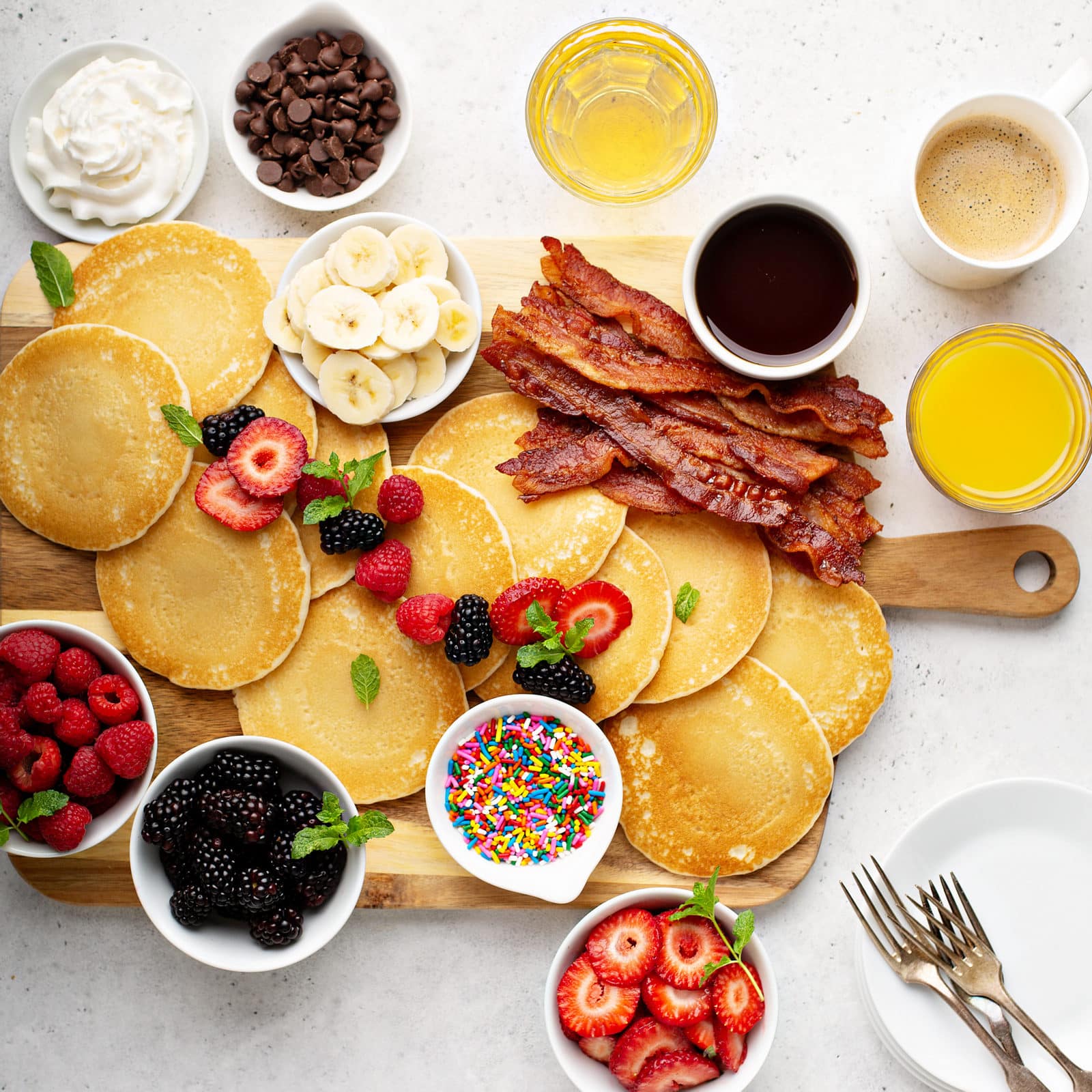 Pancake board with whipped cream, chocolate chips, bacon and fresh berries