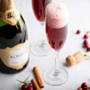 Cranberry mimosa topped with sorbet beside a Korbel bottle