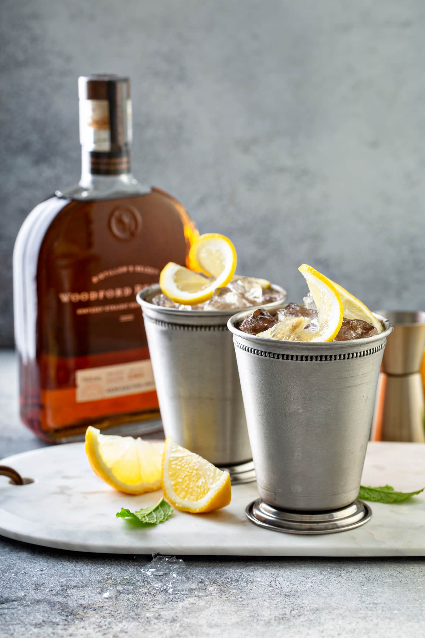 Woodford Reserve bottle with silver julep cups and lemon on a tray