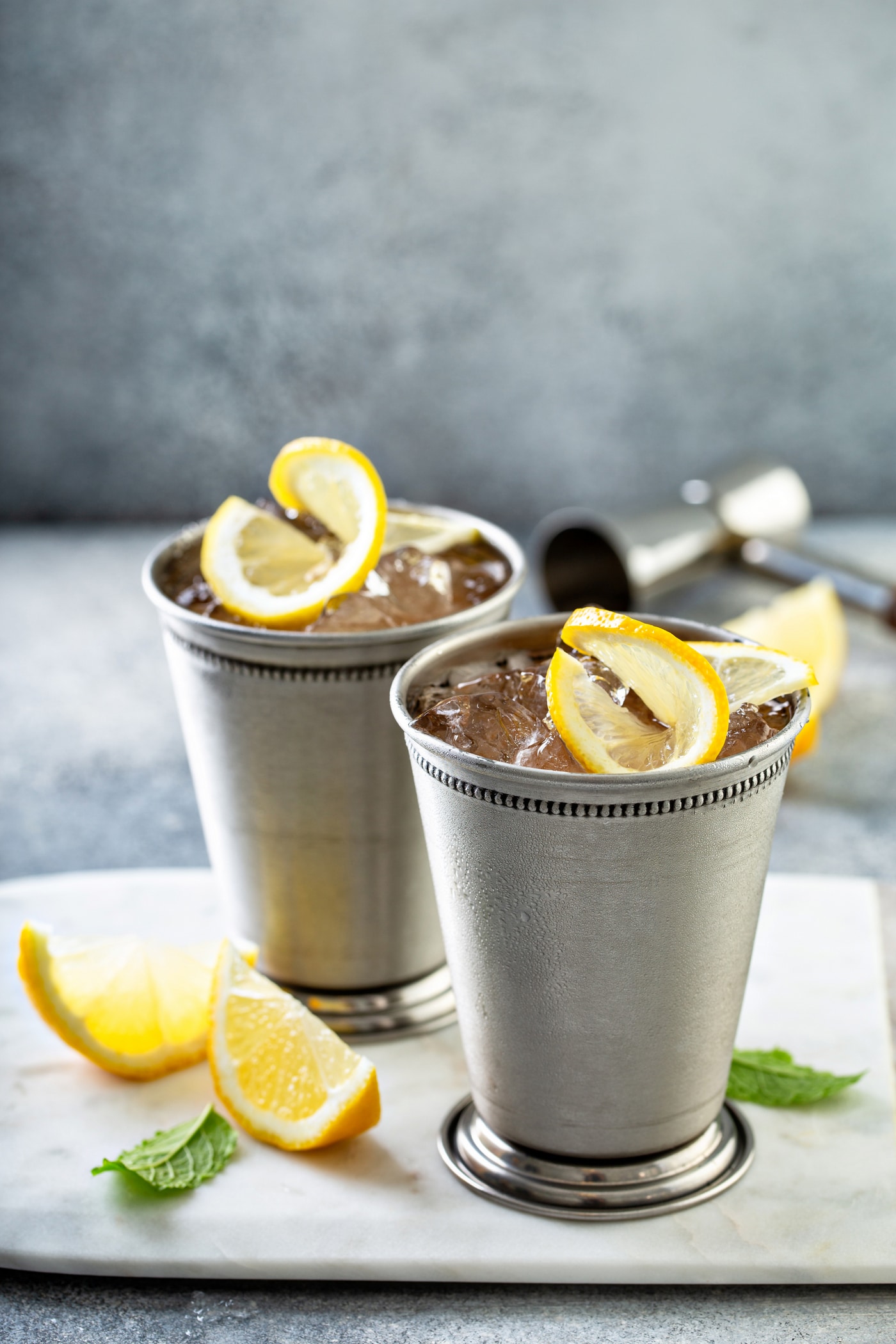 Two Woodford Spire cocktails in silver julep cups with lemon twists