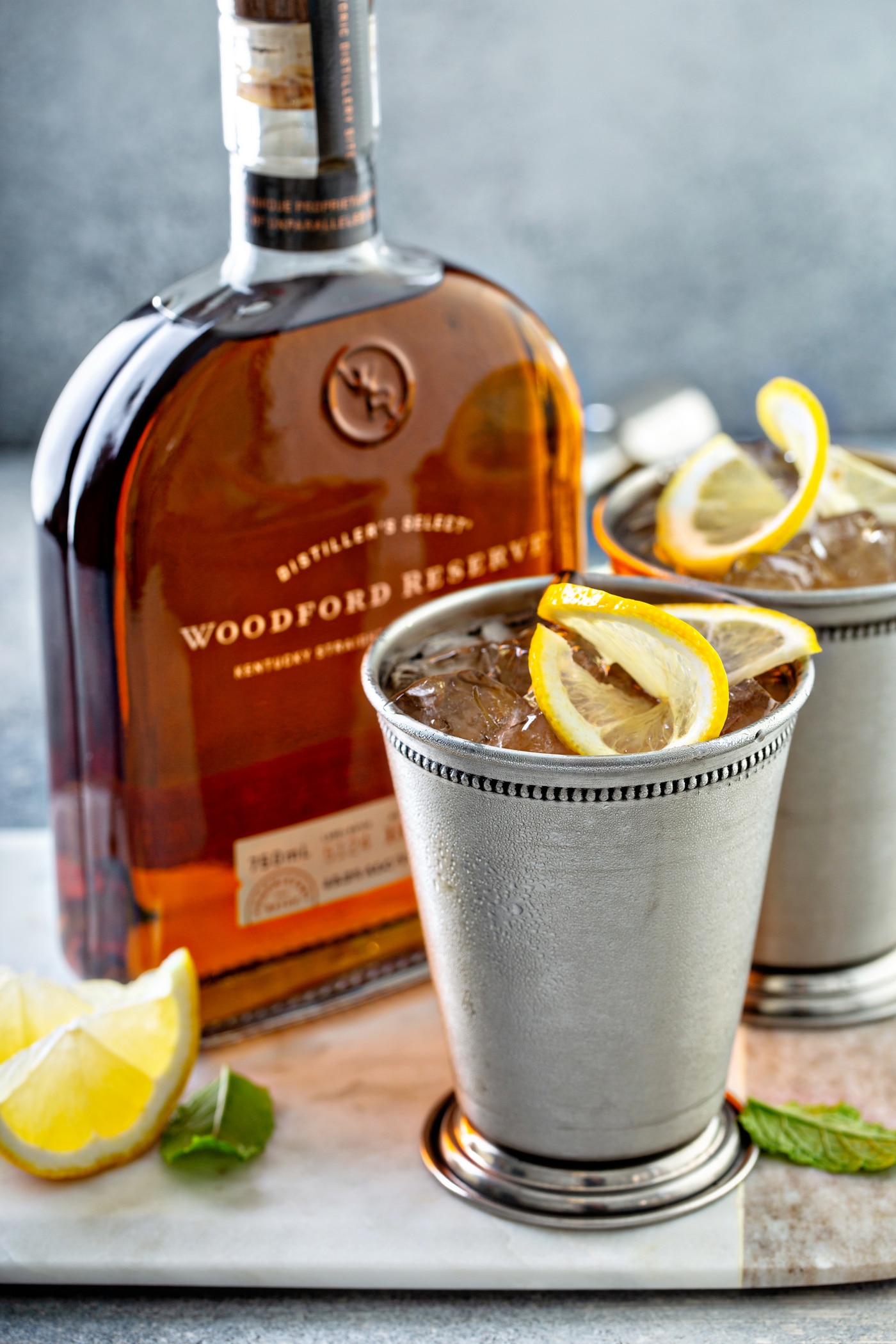 Woodford Spire cocktail in a silver cup with a lemon twist beside the bottle