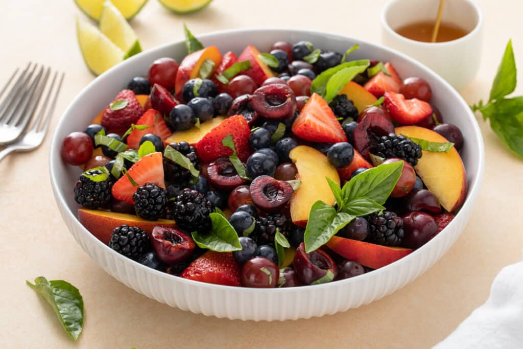 Honey Basil Peach Fruit Salad on white serving bowl