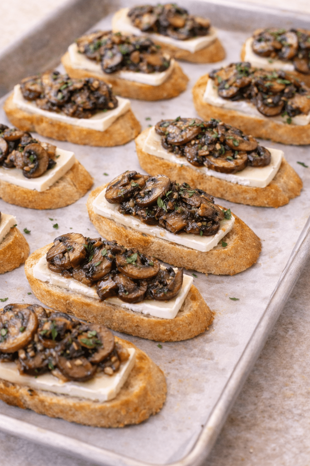 Brie slices topped with sautéed mushrooms on toasted baguette rounds