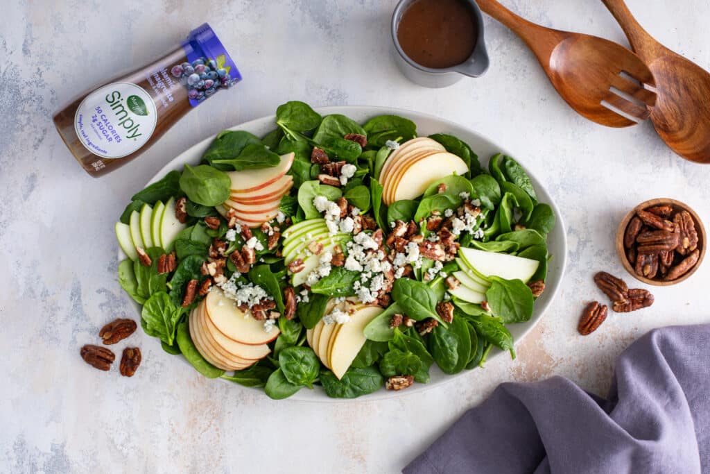 The Perfect Winter Salad served with the store bought dressing, with the pair of wooden spoon and pecans on the side