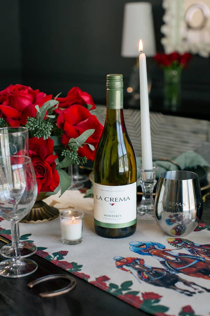 Bottle of La Crema wine beside red roses and taper candles on a Kentucky Derby table runner
