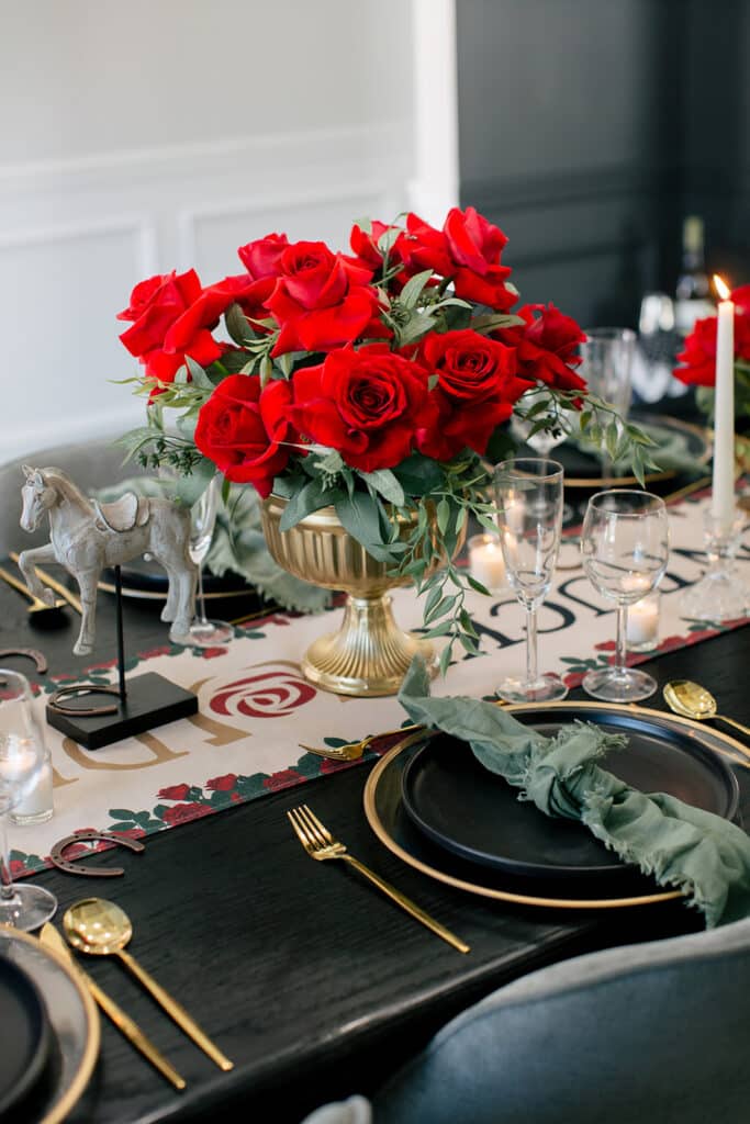 Red rose centerpiece in a gold urn on a black and gold Kentucky Derby table