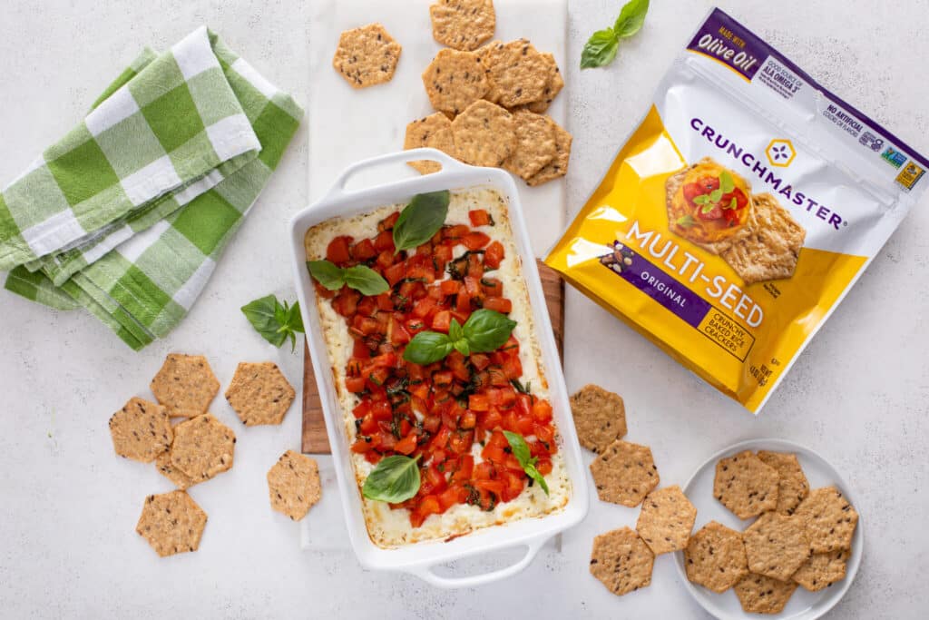 Baked goat cheese bruschetta dip topped with tomatoes and basil, served with crackers