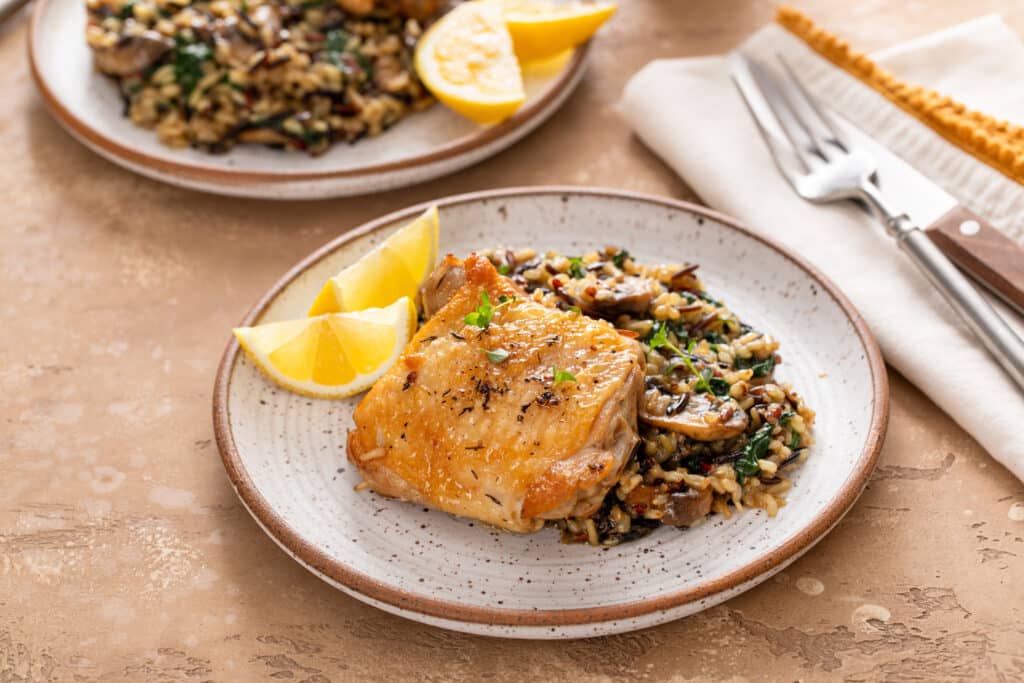 Chicken Thighs with Wild Rice on the serving plate garnished with lemon