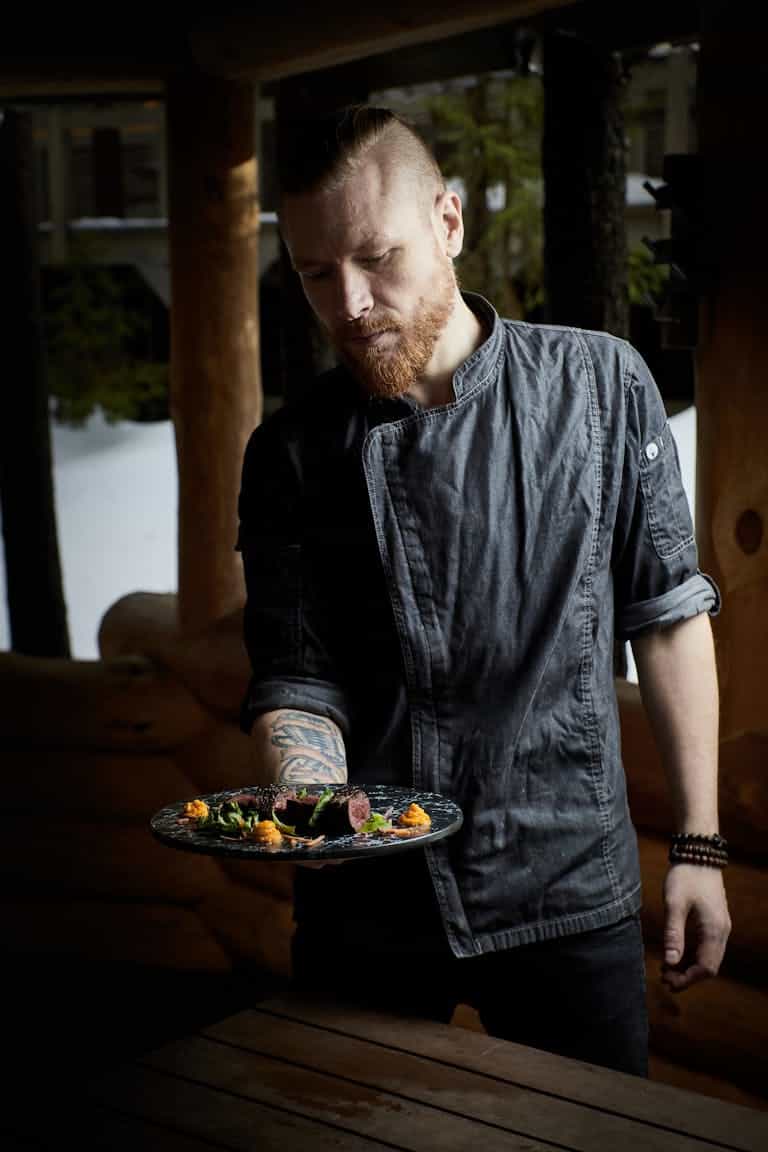 A chef showcasing a plated gourmet dish in a rustic indoors setting. Perfect for culinary themes.
