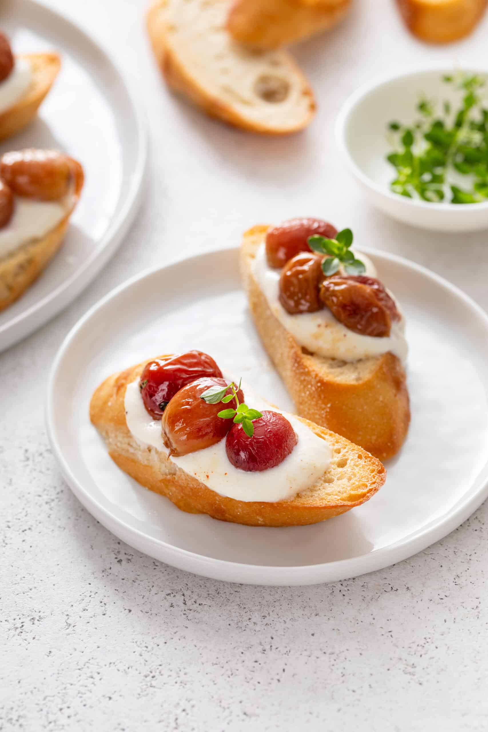bread in white plate with whipped ricotta and roasted grapes