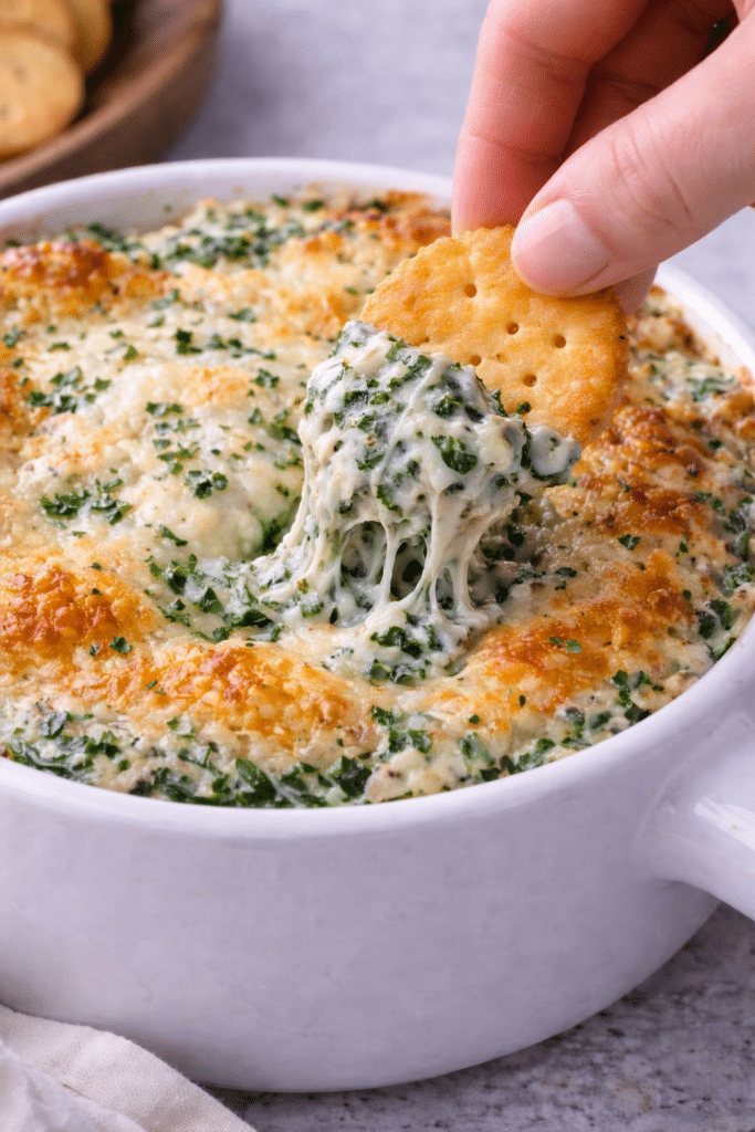 crackers dipping in creamy spinach dip