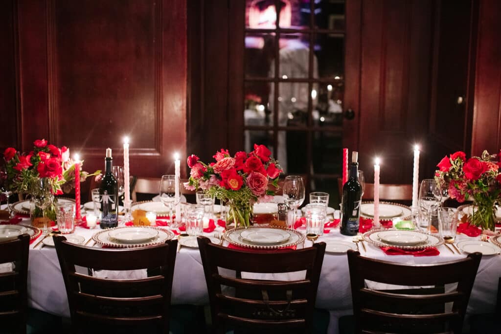 Candlelit dinner table with red rose arrangements, gold chargers, and wine bottles at Hal's Steakhouse