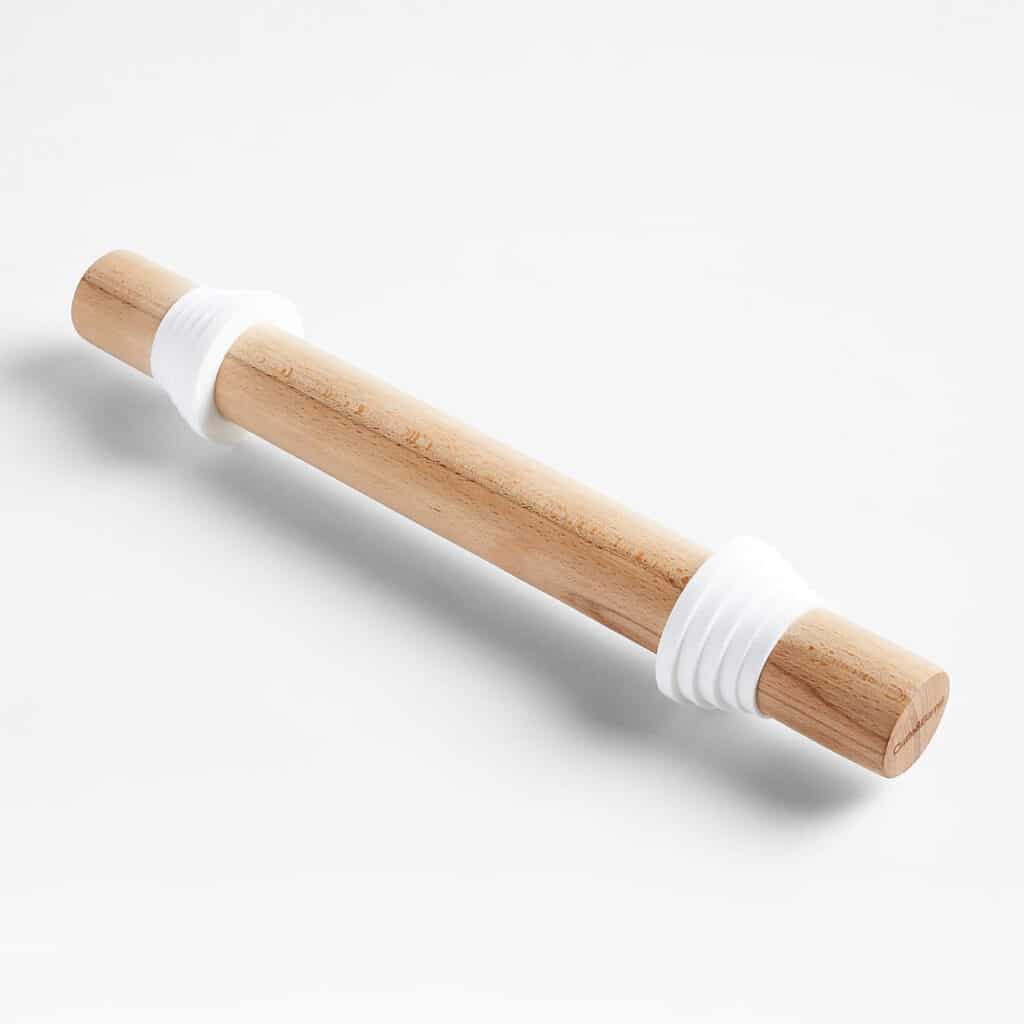 Rolling pin flattening pie dough on wooden board