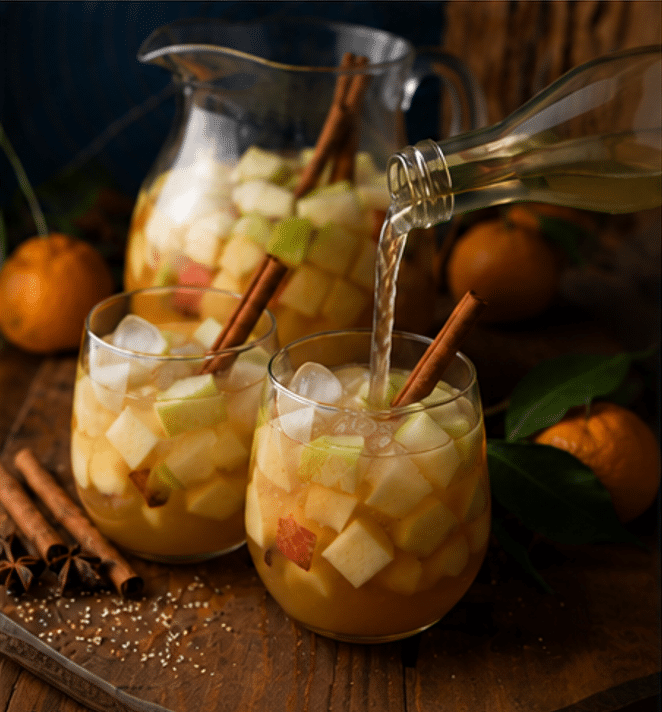 Easy Fall Apple Pie Sangria Cocktail mixed in clear glass container and filled with ice