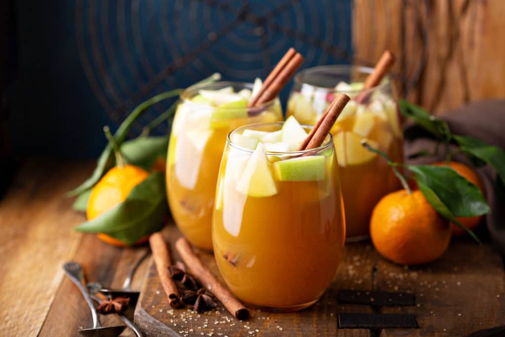 Apple pie sangria served in a glass over ice garnished with a cinnamon stick