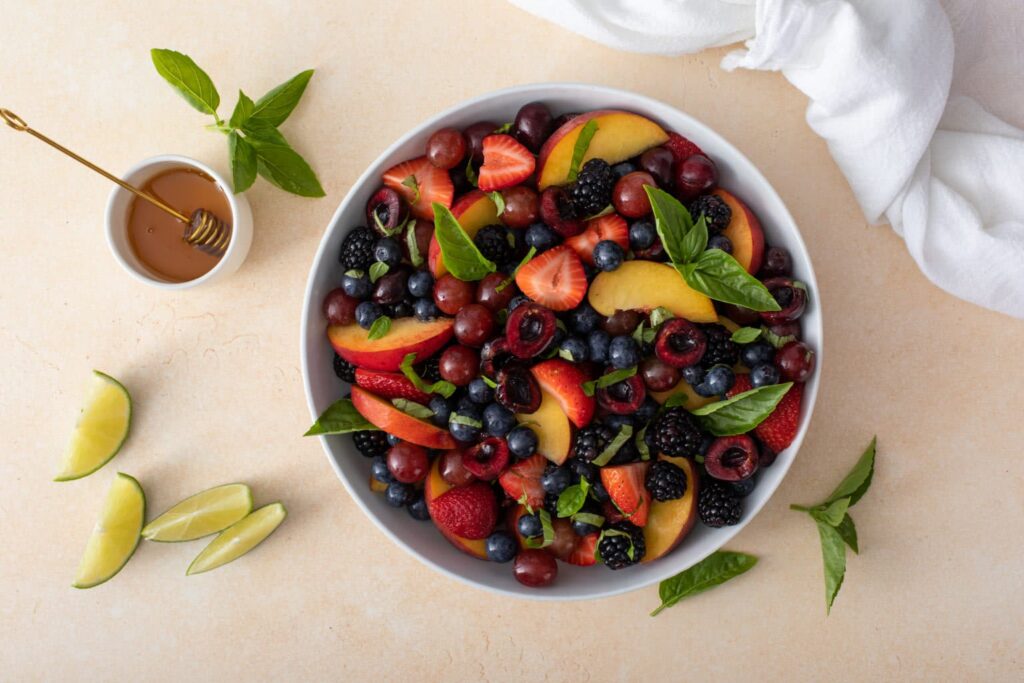 Combined ingredients and drizzle of Honey Basil Peach Fruit Salad