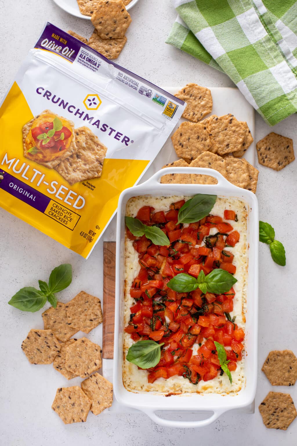 Baked goat cheese bruschetta dip in a white dish served with crackers