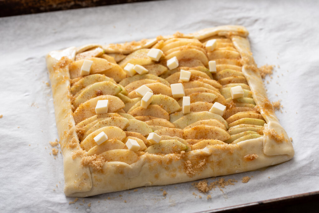 Baked apple galette on parchment with golden flaky crust