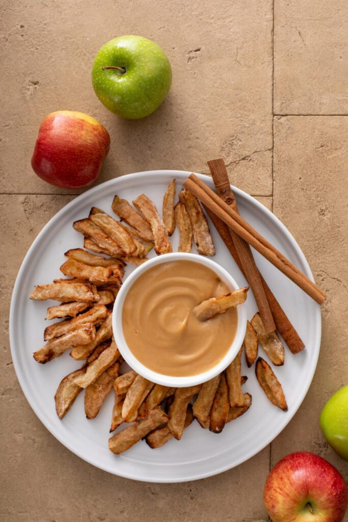 Close up Air Fryer Apple Fries with Caramel Cream Dip shot from above with cinnamon sticks and apples