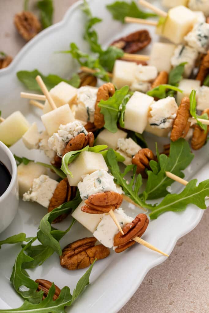 Midldle shot on the serving platter of Pear and Bleu Cheese Appetizer Skewers with Arugula and Pecans