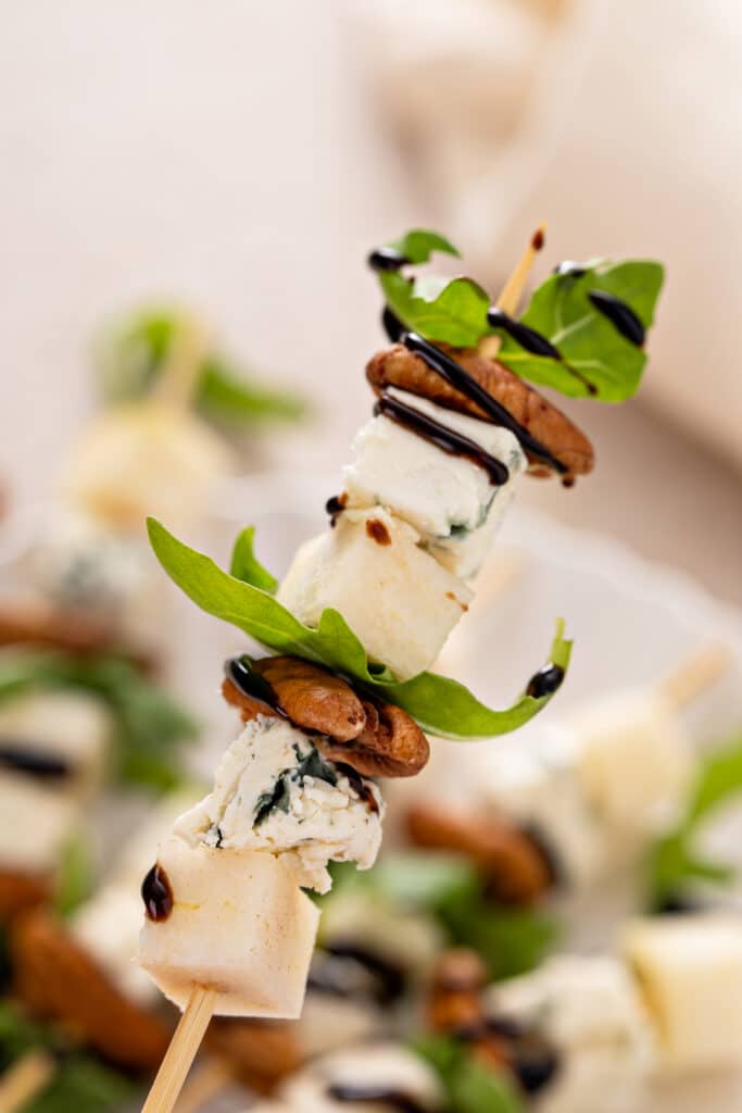 close up shot while holding the Pear and Bleu Cheese Appetizer Skewers with Arugula and Pecans