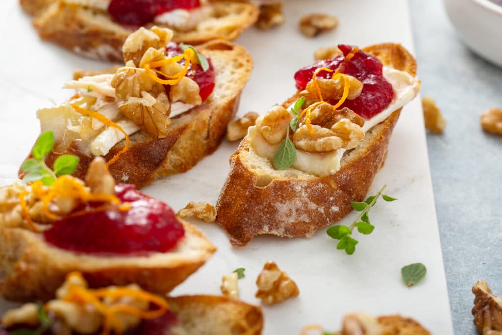 Cranberry sauce and toasted walnuts spooned over brie crostini