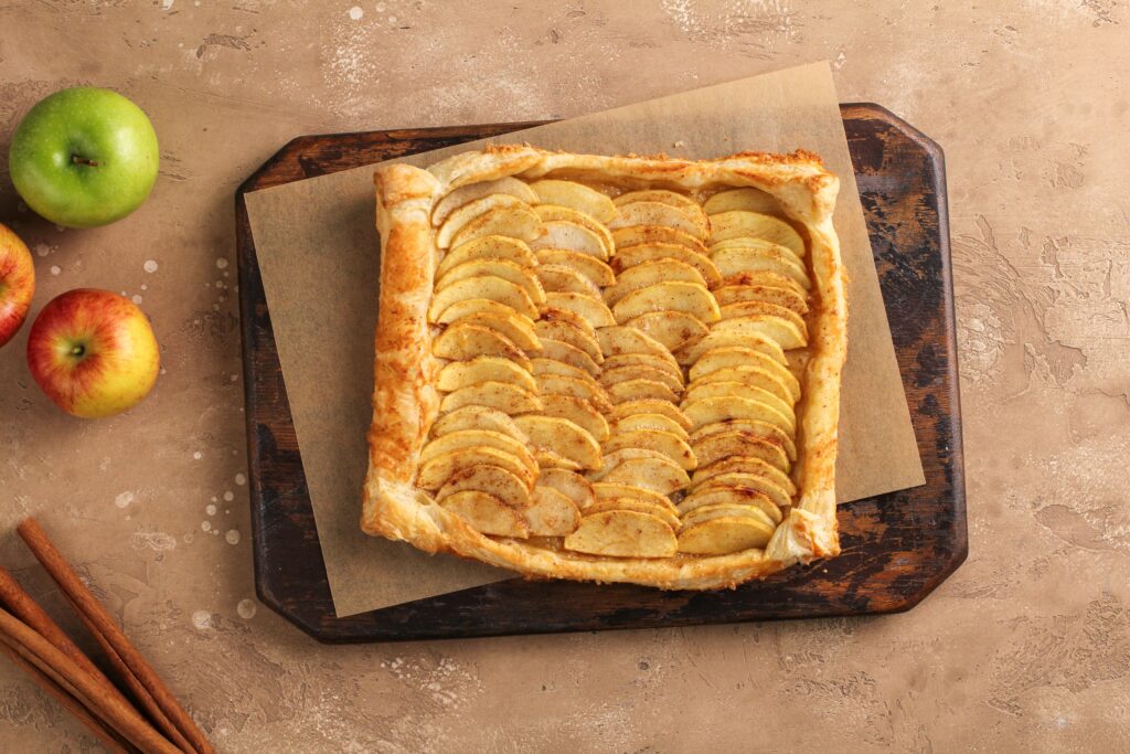 Apple galette topped with vanilla ice cream on a wooden board
