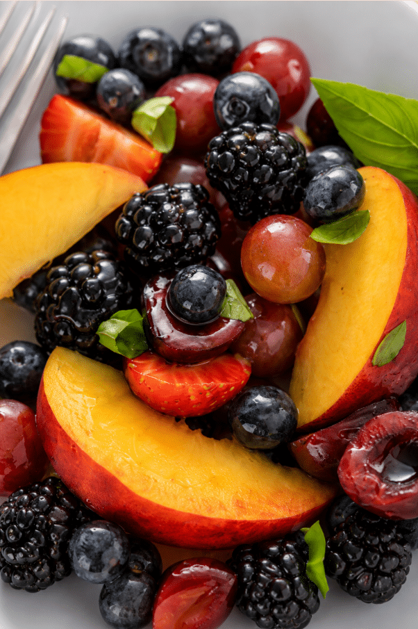 Close up shot of Honey Basil Peach Fruit Salad served in white platter