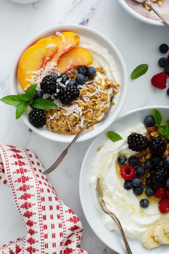 Granola and peach Greek Yogurt Bowls on the upper left and berry version
