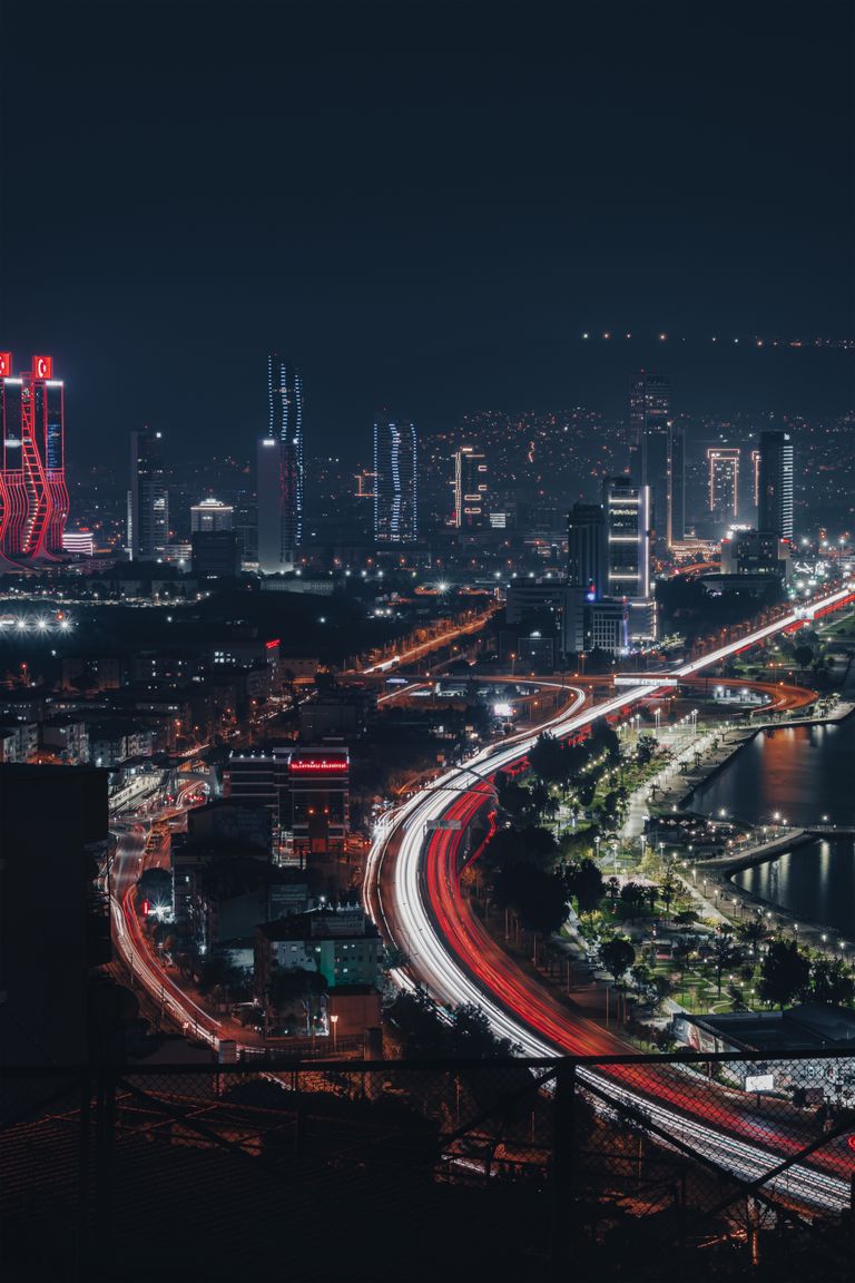 Stunning nighttime cityscape of İzmir featuring skyscrapers and light trails from traffic.