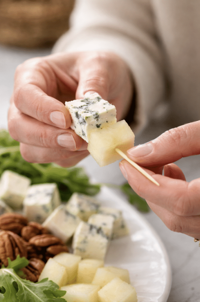 assemble of skewers starting with Pear goat cheese, Pear and Bleu Cheese Appetizer Skewers with Arugula and Pecans