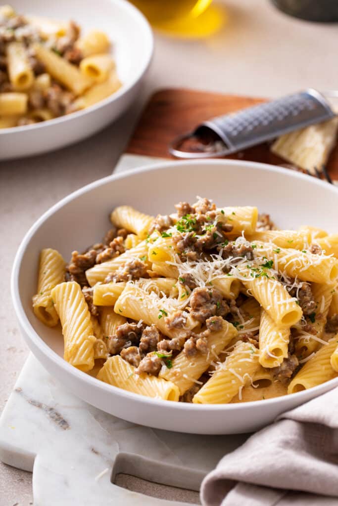 sausage rigatoni in white pasta bowl with fresh parsley and parmesan for dinner party image