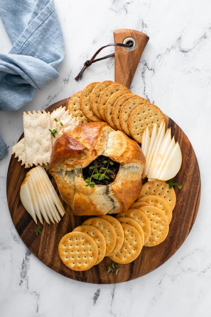 Baked Brie With Balsamic Caramelized Onions served in wooden platter