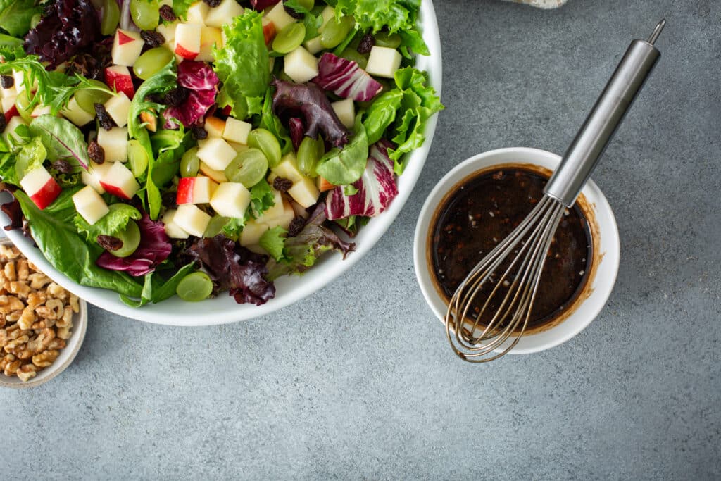 Image of Apple and Goat Cheese Salad with dressing and nuts on the side