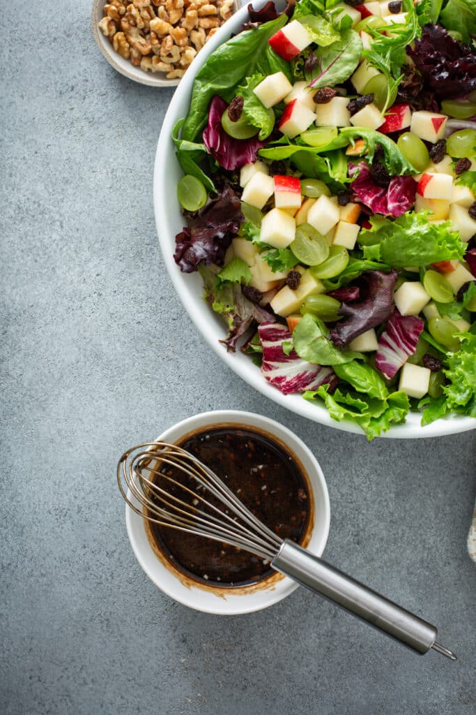 Image of Apple and Goat Cheese Salad with dressing and nuts on the side