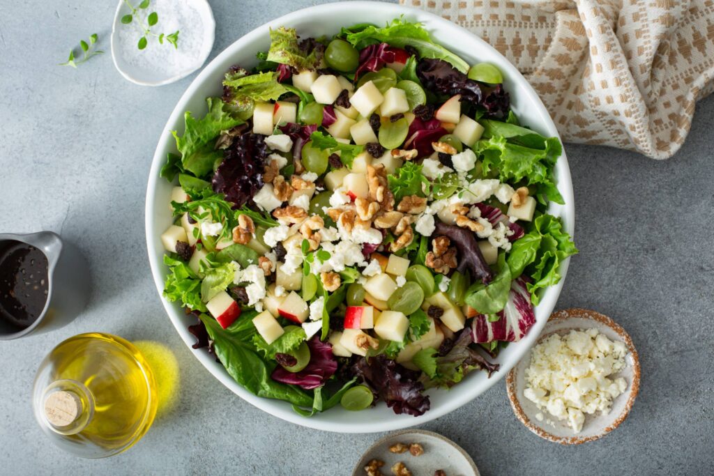 Apple and Goat Cheese Salad on a serving plate image with salt, olive oil, goat cheese on the side