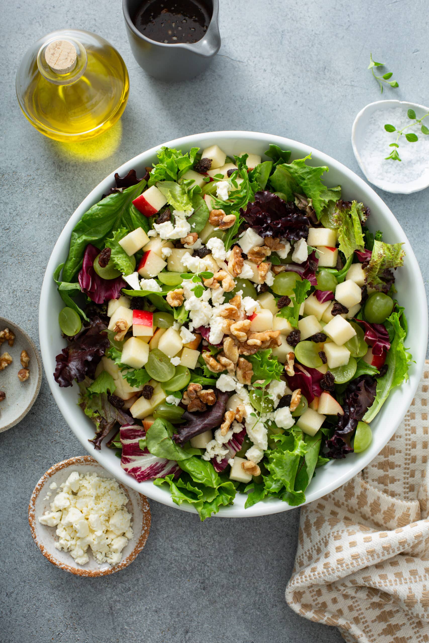 Apple and Goat Cheese Salad on a serving plate image with salt, olive oil, goat cheese on the side