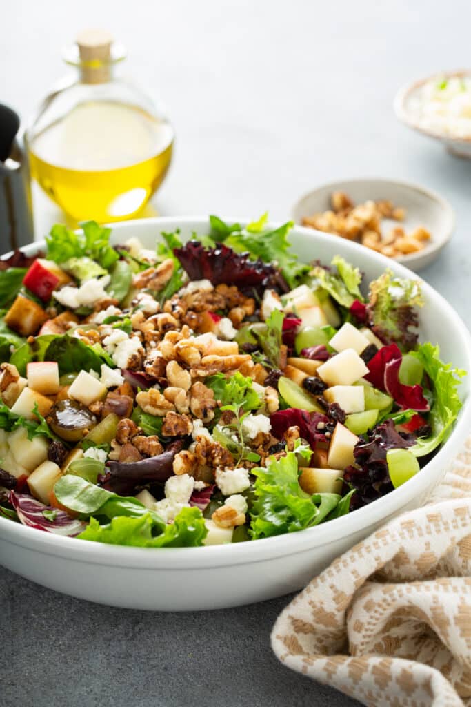The greens mixed together with apple, raisings nuts build the Apple and Goat Cheese Salad