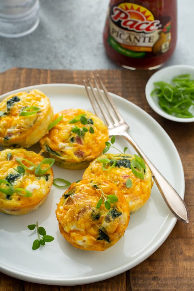 Served in white platter the Bacon Spinach & Cheese Egg Muffins with Pace picante sauce on the picture