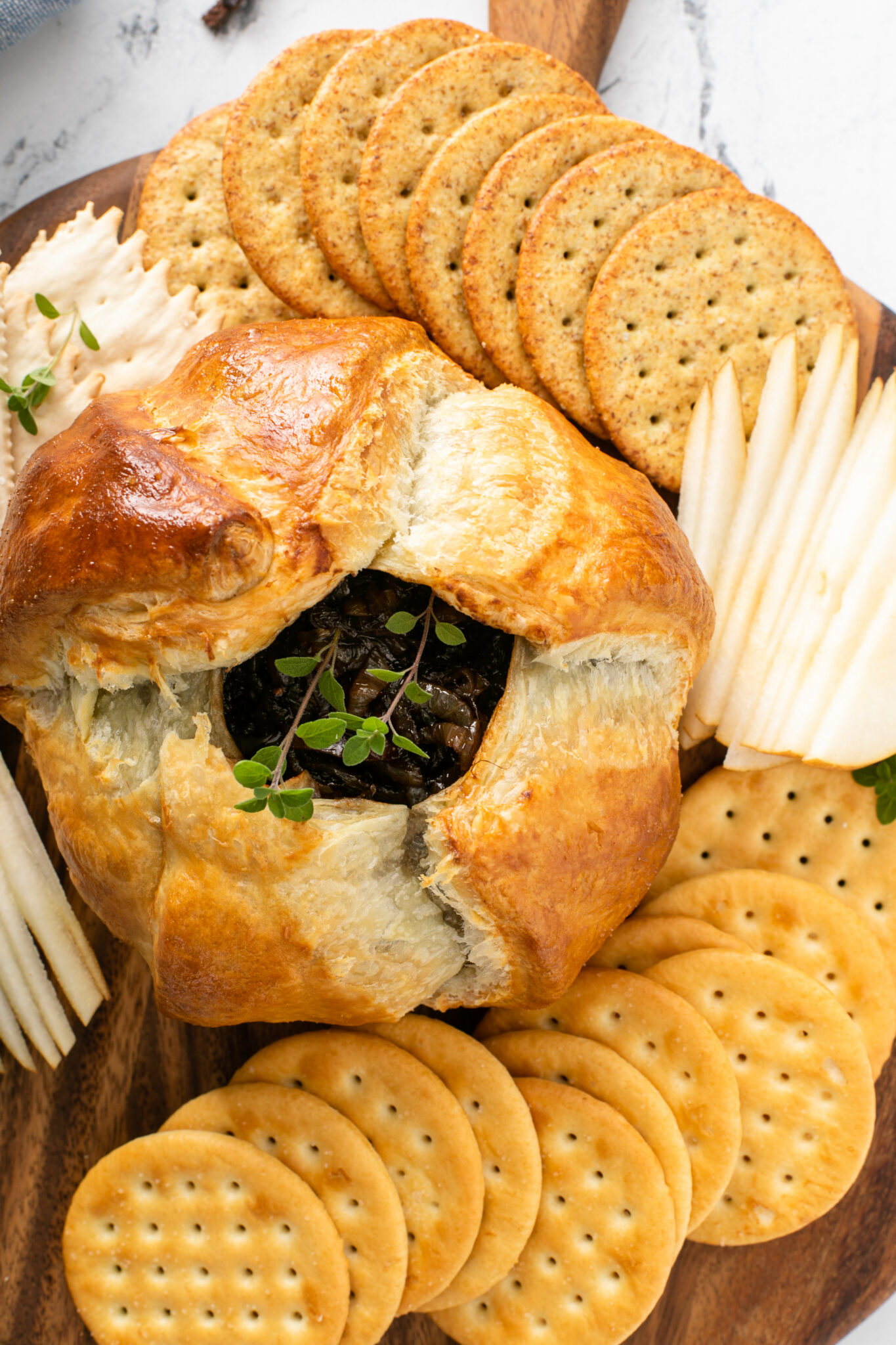 Baked Brie With Balsamic Caramelized Onions served with crackers and fruit slices, close up shot