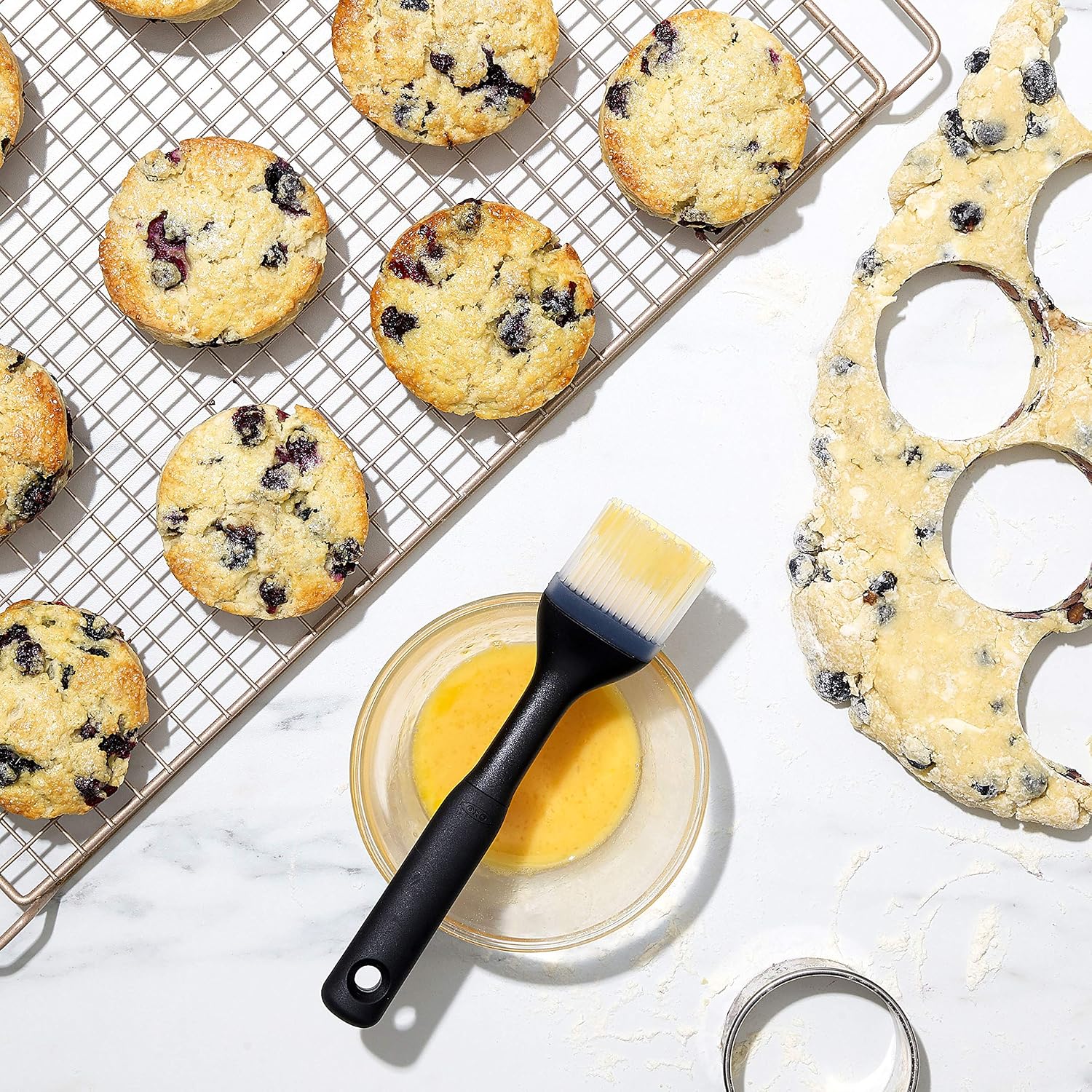 Blueberry scones cooling on a wire rack beside a pastry brush
