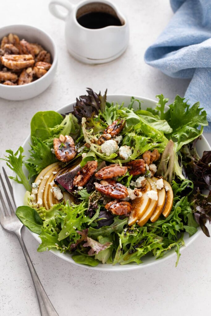 Freshly served Pear & Gorgonzola Salad with Candied Pecans with dressing and pecans in the picture