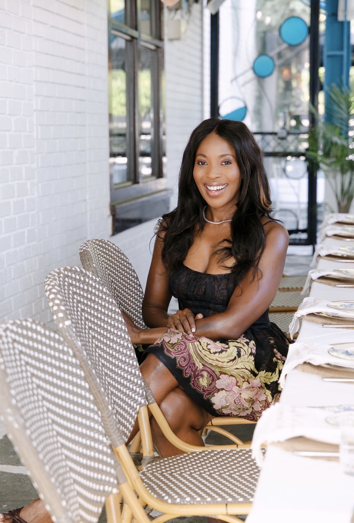 Erica Thomas seated at a Greek-inspired dinner party table set with Lenox china and embroidered napkins