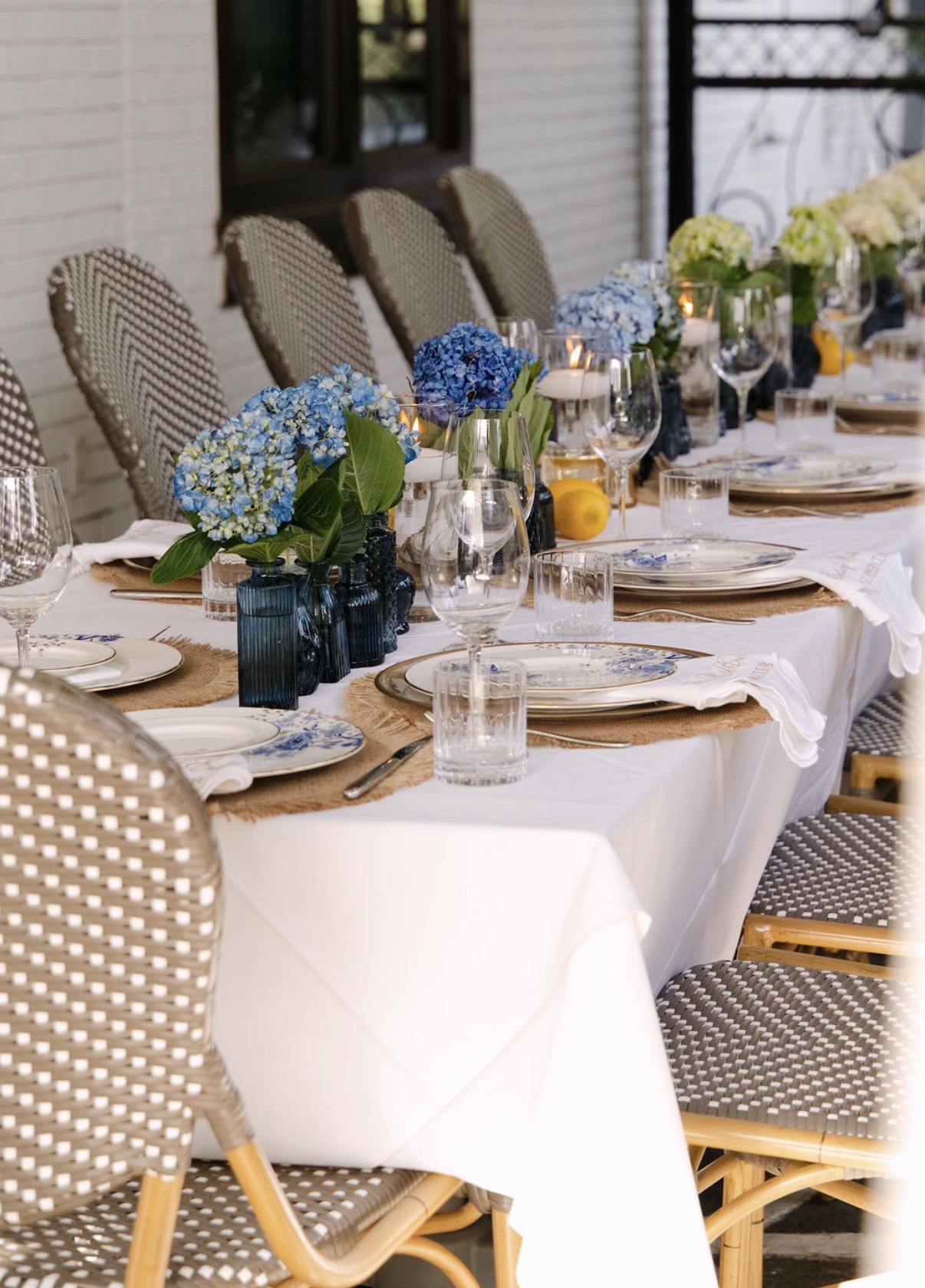 White and green hydrangeas in blue glass bud vases with floating candles along a dinner party table