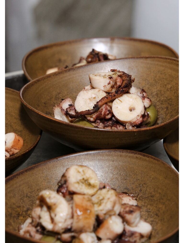 Kyma's wood-grilled octopus plated in rustic ceramic bowls