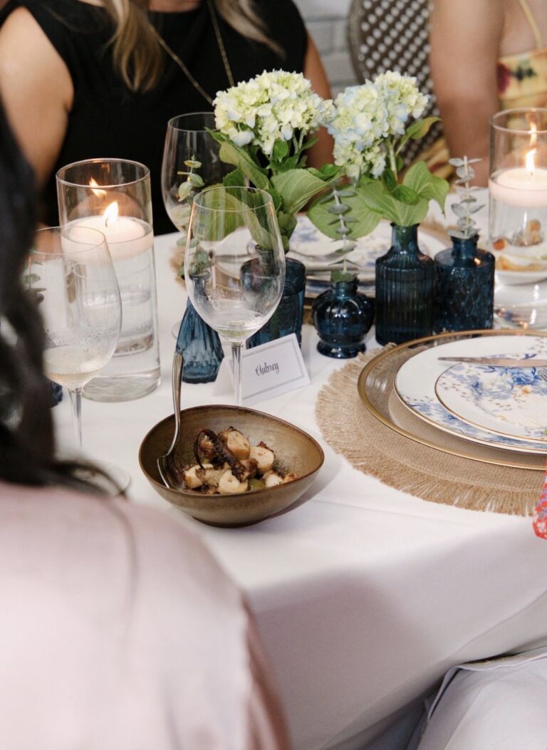 A bowl of grilled octopus served family style on the Supper Club table at Kyma, with white hydrangeas, blue bud vases and floating candles