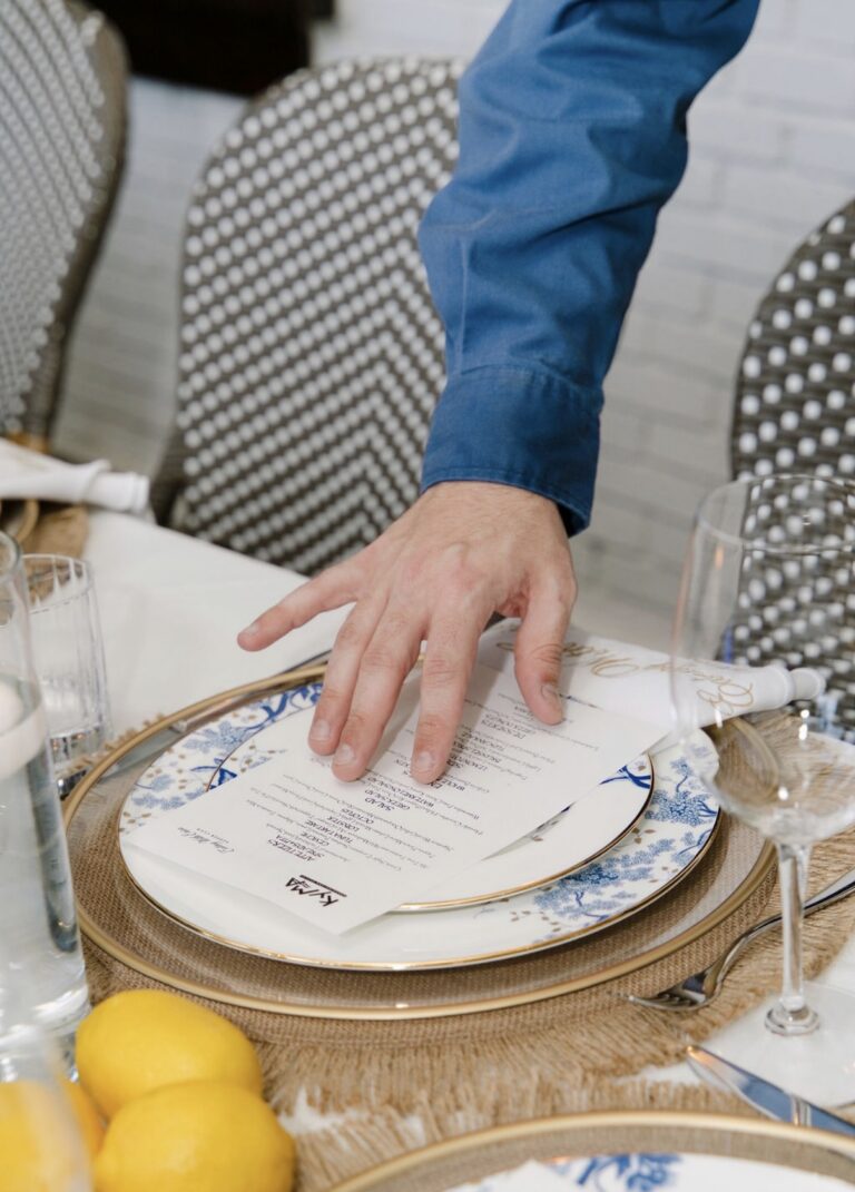 A Kyma menu being placed on a Lenox Garden Grove plate at the Eating With Erica Supper Club dinner