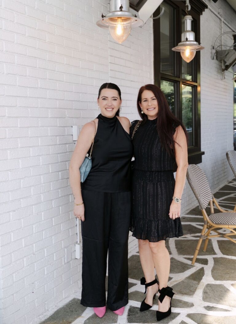 Two Supper Club guests smiling together on the white brick patio at Kyma