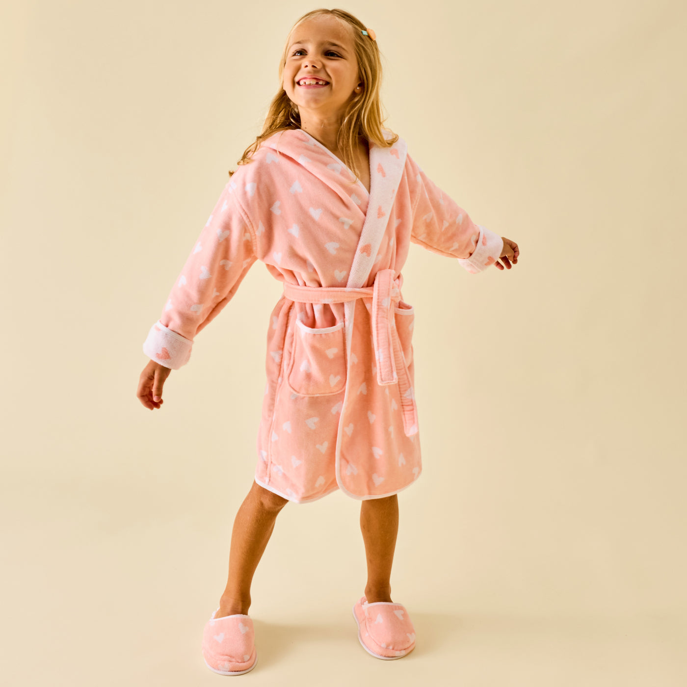 Young girl wearing a pink plush Weezie kids bathrobe with matching slippers