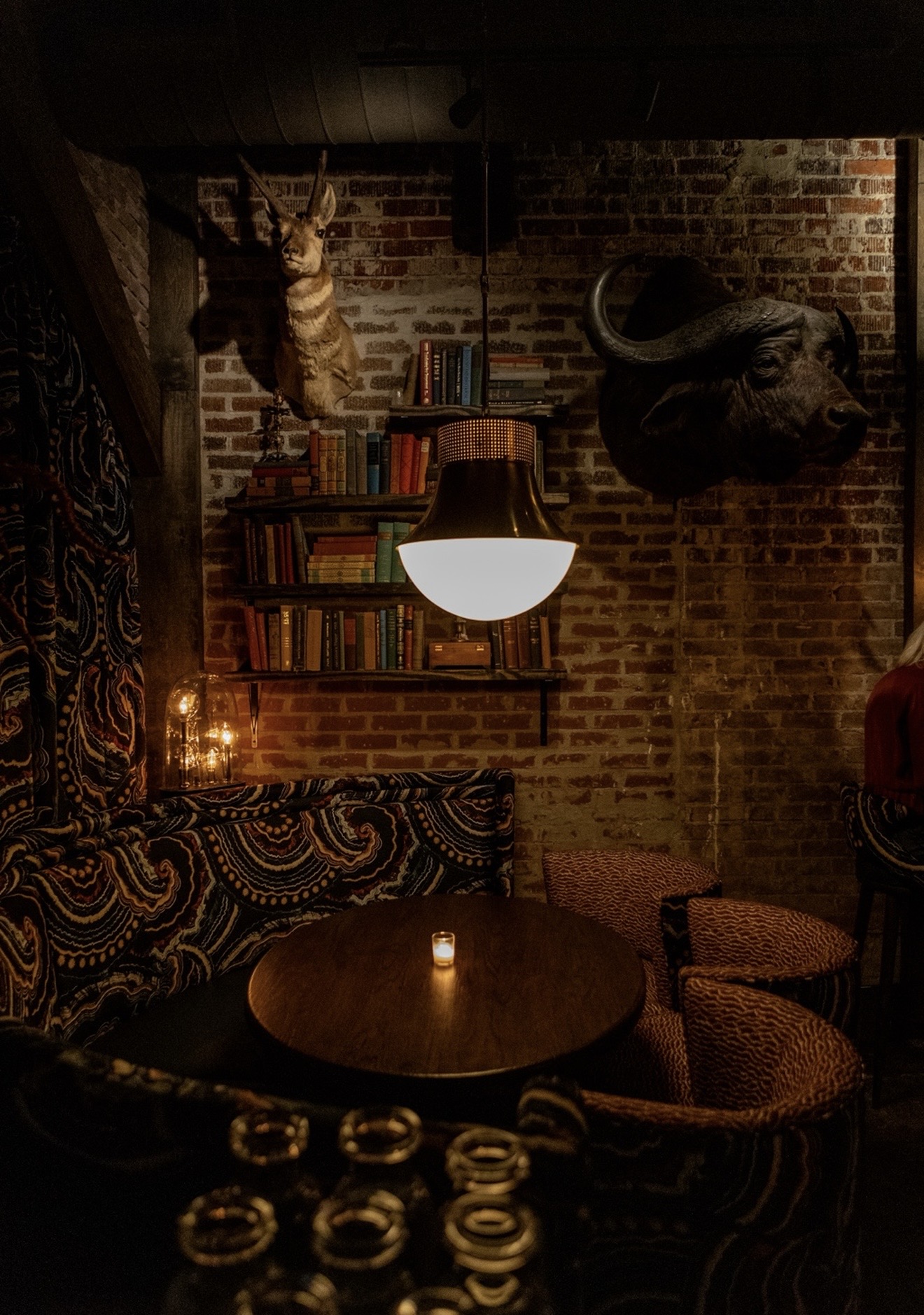 The candlelit bar room at Miscellanea Spirit House in Oxford, Mississippi, with brick walls and mounted trophies